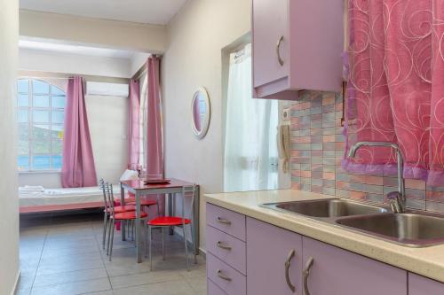 eine Küche mit rosa Schränken, einem Waschbecken und einem Fenster in der Unterkunft Wavedance Accommodation in Salamís