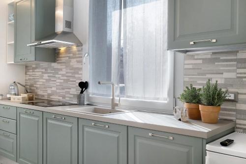 Una cocina con gabinetes blancos y un fregadero y una ventana. en Baita Marina - Libeccio 30m mare, en Ceriale