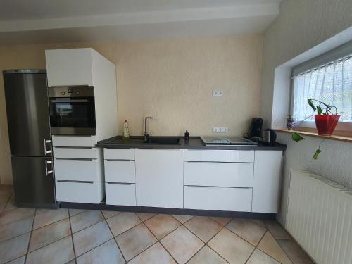 a kitchen with white cabinets and a stainless steel refrigerator at Belroki Ranch in Waldeck