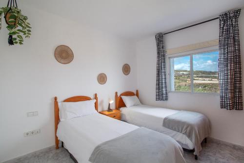 two beds in a room with a window at Los Adejo vacacional in Moya