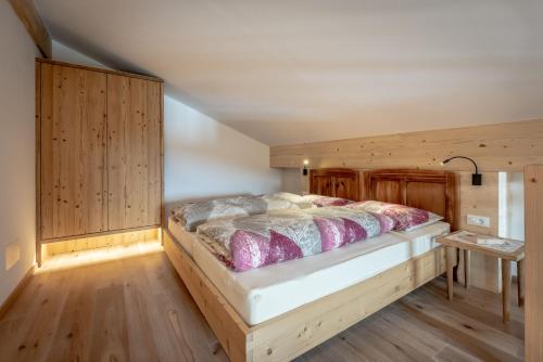 Un dormitorio con una cama en una habitación de madera. en Oberprünst Hof - App. St. Sebastian, en Plazzoles