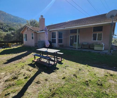 a picnic table with an umbrella in front of a house at The Gathering Spot-6 miles from Sequoia Nlt'l Park in Three Rivers