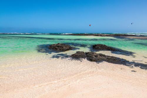 una spiaggia con alcune rocce nell'acqua di Casa Orymar a Cotillo