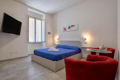 a bedroom with a blue bed and two red chairs at Casa Vacanza Soffio in Alghero