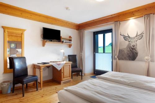 a bedroom with a bed and a desk with a deer on the wall at Landgasthof Bergblick in Bernau im Schwarzwald