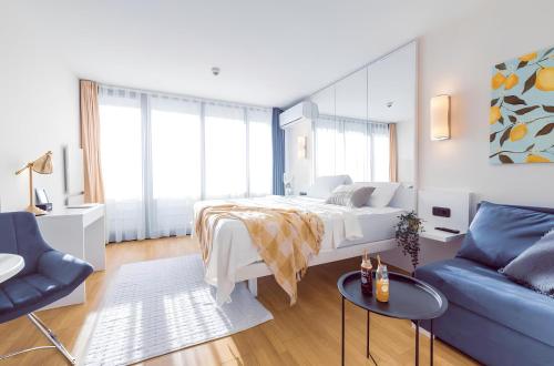 a bedroom with a bed and a blue couch at Vibrant & Modern ORBi CiTY Apart-Hotel in Batumi
