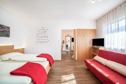 - une chambre avec deux lits et un canapé rouge dans l'établissement Schnitzer Ferienwohnung Hagebutte, à Rablà