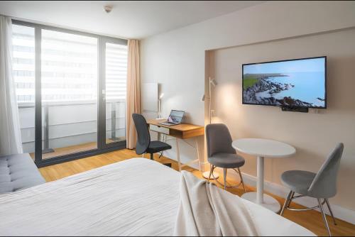 Un dormitorio con una cama y un escritorio y sillas. en Panorama Batumi Beach Resort, en Batumi