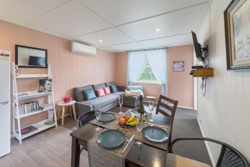 a living room with a table and a couch at Isobel's Rose Cottage in Hanmer Springs