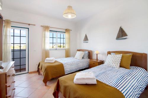 a bedroom with two beds and a bathroom with windows at Villa Alagoa in Altura