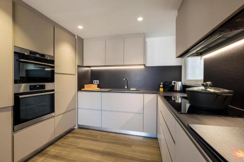 ラルプ・デュエズにあるTriplex By Popalpの白いキャビネットとシンクのあるキッチン