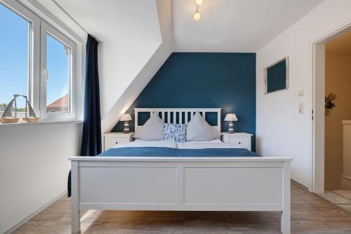 a bedroom with a white bed with a blue wall at Ferienhaus Düün Drööm in Ording