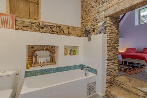 a bathroom with a bath tub and a stone wall at La Dordogne en Périgord in Salagnac
