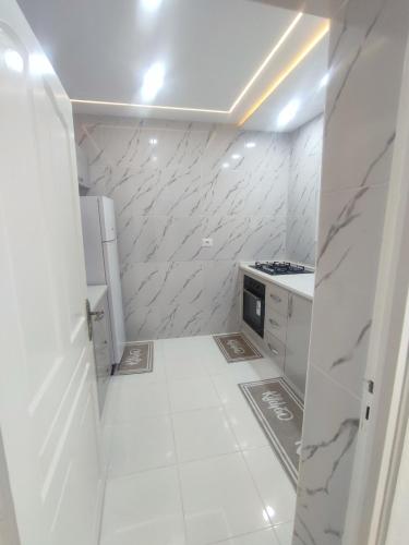 a white kitchen with a white floor and white appliances at Charmant T3 in Houmt Souk