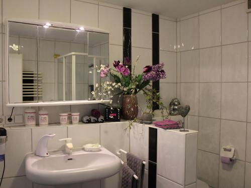a bathroom with a sink and a mirror and flowers at Villa Black Forest in Adelhausen