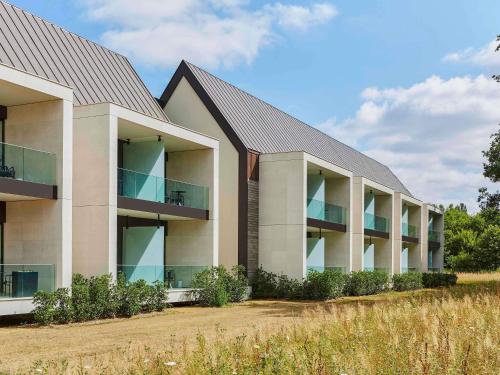 an apartment building with balconies in a field at Le Domaine des Vanneaux Golf & Spa L'Isle Adam - MGallery Collection in LʼIsle-Adam