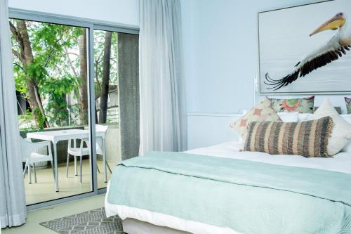 a bedroom with a bed and a balcony with a table at The Village Suites in Windhoek