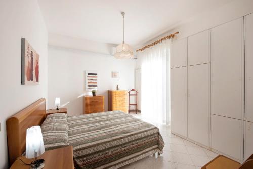 a white bedroom with a bed and a dresser at Trilocale Mazzini con 2 balconi in Varazze