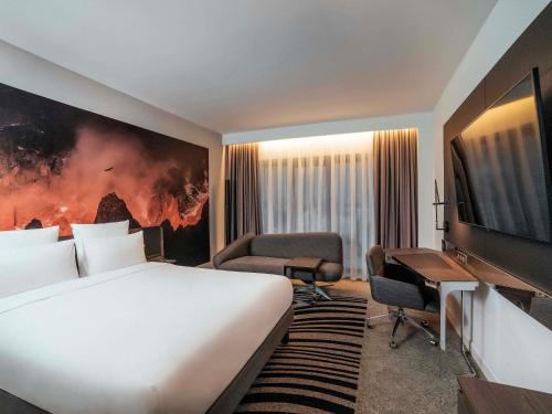 a hotel room with a large bed and a desk at Novotel Bishkek City Center in Bishkek