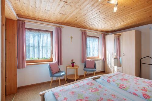 Schlafzimmer mit 2 Stühlen, einem Bett und Fenstern in der Unterkunft Ferienappartement Gisela in Bernau im Schwarzwald
