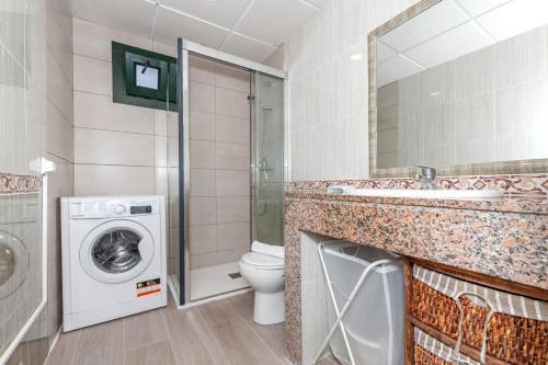 a bathroom with a sink and a washing machine at Apartamento Biniforcat in Cala en Forcat
