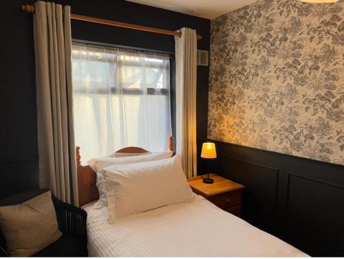 Rooms Foxford في فوكسفورد: غرفة نوم صغيرة بها سرير ونافذة