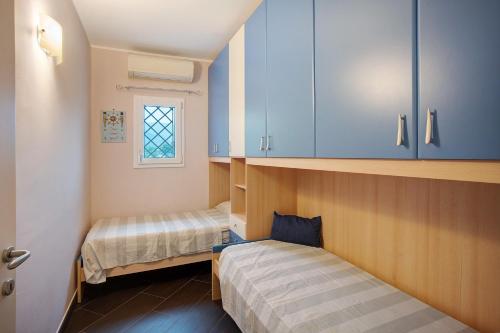 a small room with two beds and blue cabinets at Trilocale Con Piscina Vista Mare in Diano Castello