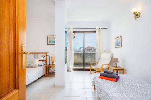 een slaapkamer met twee bedden en een stoel en een raam bij Atico Roger De Flor in Pollença