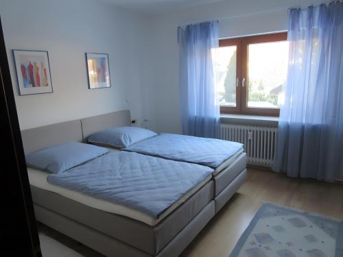 une chambre avec un lit avec des draps bleus et une fenêtre dans l'établissement Ferienwohnung Kreuzbühl, à Albstadt