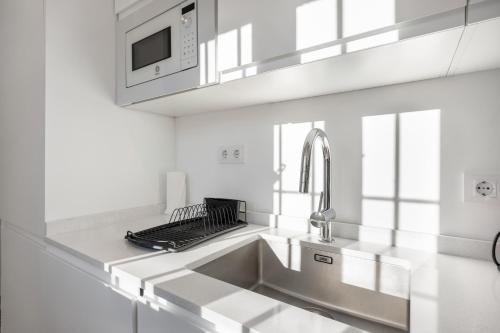 eine weiße Küche mit Spüle und Mikrowelle in der Unterkunft Ático San Jose in Cádiz