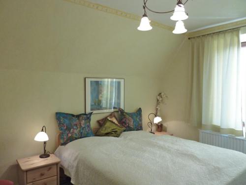 a bedroom with a bed with two lamps and a window at Ferienwohnung Wunschgarten in Wesselburen