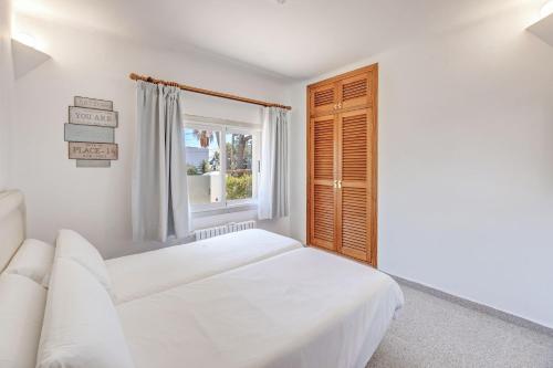 a white bedroom with a bed and a window at Sant Antoni in Santanyi
