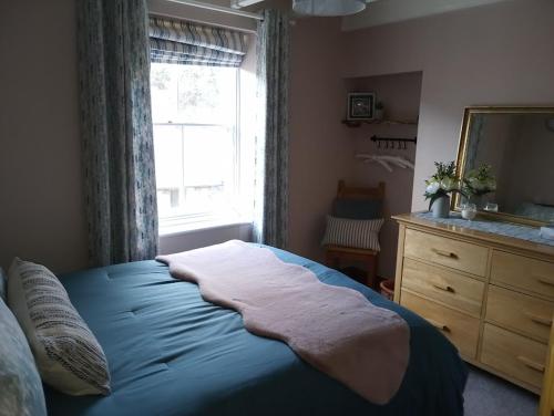 a bedroom with a bed with a window and a dresser at Rose Lea, Beautiful Seaside Home in Staithes