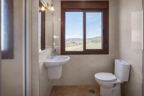 a bathroom with a toilet and a sink and a window at Plaza Iglesia in Frigiliana
