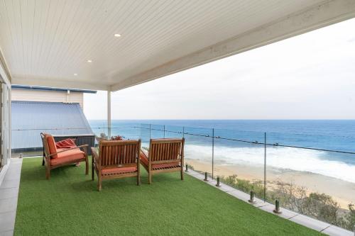 two chairs and a table on a balcony with the beach at Flatrock Penthouse Ulladulla in Ulladulla