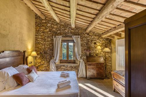 a bedroom with a large bed in a stone wall at Can Riera de la Pineda in Girona