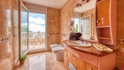 a bathroom with a sink and a toilet and a window at Costacabana - Villa Ibiza in Lloret de Mar