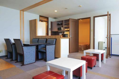 a room with a table and chairs and a kitchen at コンドミニアム白馬五竜 in Hakuba