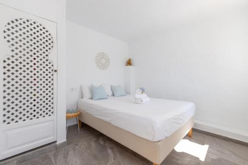 ein weißes Schlafzimmer mit einem weißen Bett und blauen Kissen in der Unterkunft Apto Jazmin con piscina en Riad in Torremolinos