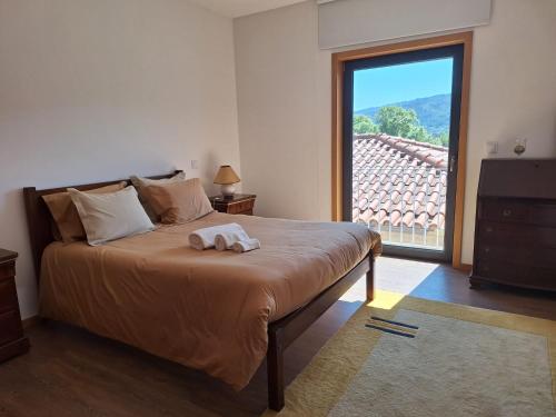 ein Schlafzimmer mit einem Bett und einem großen Fenster in der Unterkunft Casa Vilarinha Gerês in Taboabela