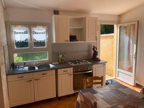 una cucina con mobili bianchi, un lavello e una stufa di Camping les Pialades - Gite a La Mouline