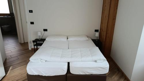 two beds in a small room with white sheets at Appartamento Via Livigno in Isolaccia