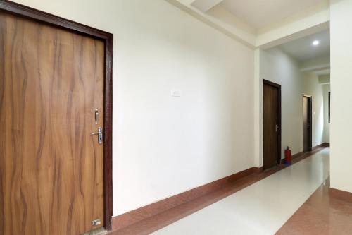 a hallway with a wooden door in a house at Hotel O White House in Patna