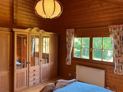 ein Schlafzimmer in einem Blockhaus mit einem Bett und Fenstern in der Unterkunft Landhaus An der Schafgasse in Spittelstein