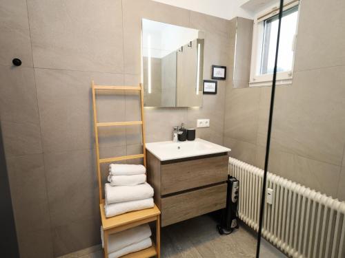 une salle de bain avec un lavabo, un miroir et des serviettes dans l'établissement Tirola Platzl, à Hopfgarten im Brixental