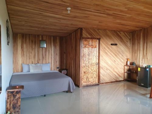 a bedroom with a bed and a wooden wall at El Chagüite monteverde #2 in Monteverde Costa Rica