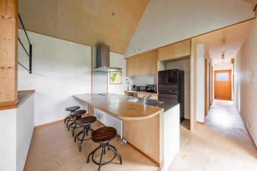 a kitchen with a counter and stools in it at Poroto House in Nanae