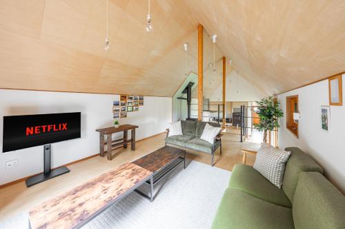 a living room with a couch and a tv at Poroto House in Nanae
