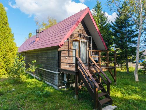 a tiny house with a red roof and a staircase at Poroto House in Nanae