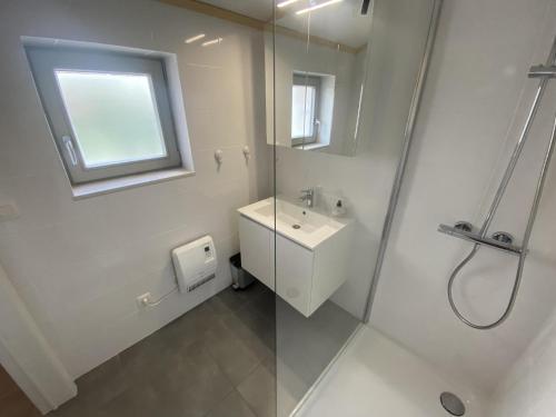 Un baño blanco con lavabo y ducha en Westhinder II H52, en Koksijde